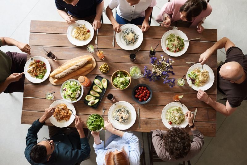 A group of people sharing a meal together at a long wooden table, seen from above