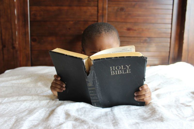 A young boy reading an open Holy Bible