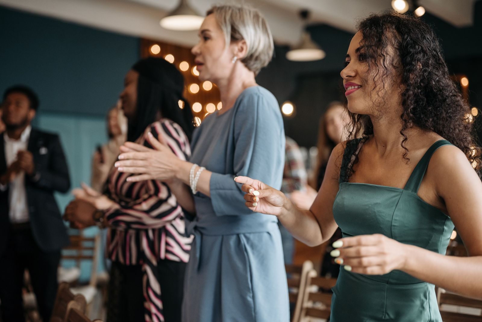 Members of a church congregation standing together during worship, singing and clapping