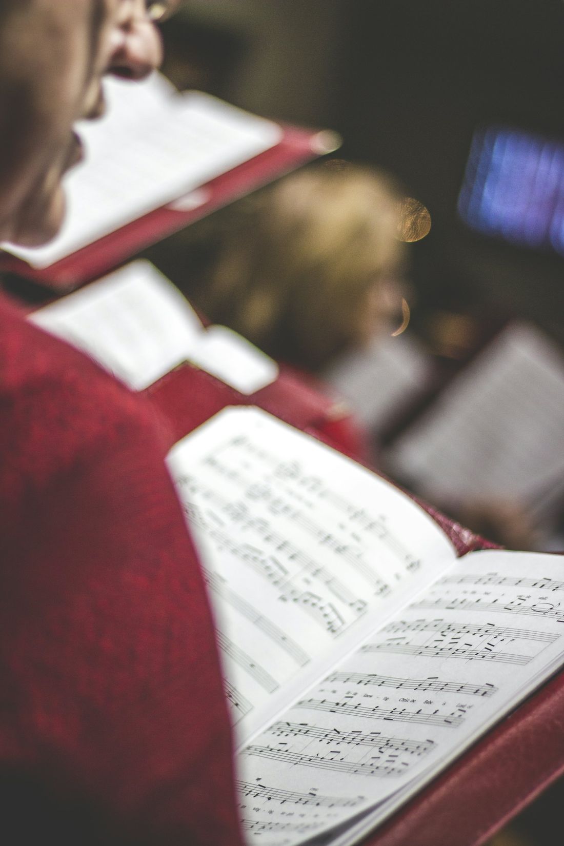 Close-up of people in a church holding open songbooks and singing together